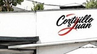 Fachada blanca del restaurante El Cortijillo de Juan con el rótulo negro sobre la pared